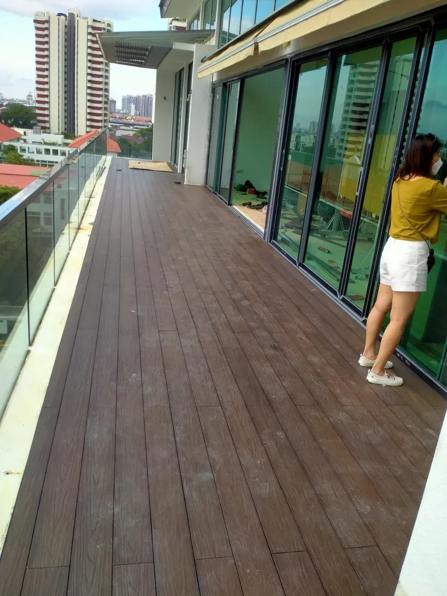 Composite timber decking on a Singapore condominium balcony with a glass railing
